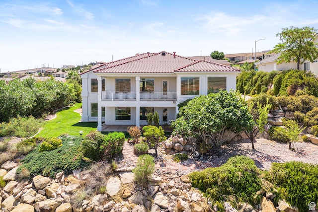 back of property featuring a balcony, a tile roof, and stucco siding