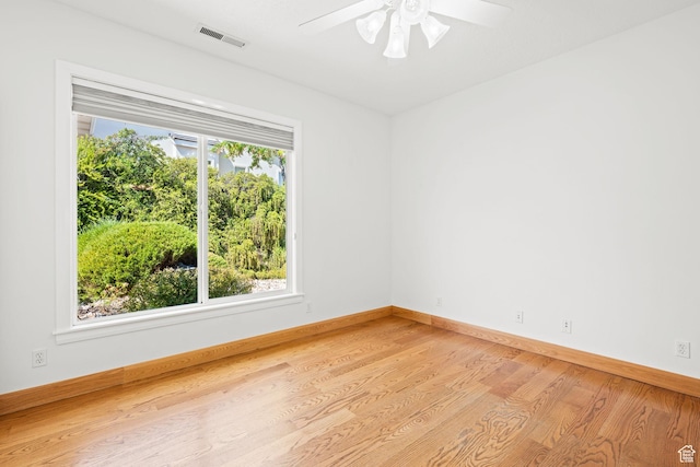 spare room with a ceiling fan, light wood-type flooring, visible vents, and baseboards
