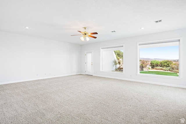 carpeted empty room with visible vents, a textured ceiling, and baseboards