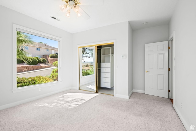 unfurnished bedroom featuring a closet, light colored carpet, visible vents, ceiling fan, and baseboards