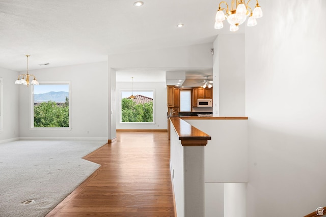 interior space featuring brown cabinetry, dark countertops, white microwave, pendant lighting, and a wealth of natural light
