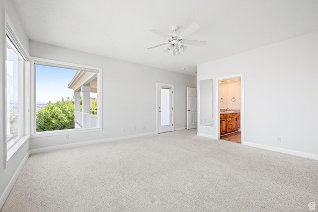 unfurnished bedroom featuring baseboards, a sink, connected bathroom, and light colored carpet
