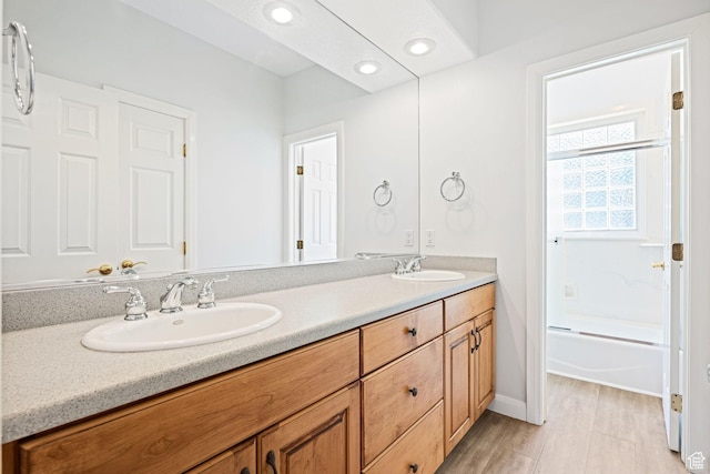 bathroom featuring double vanity, bathtub / shower combination, a sink, and recessed lighting