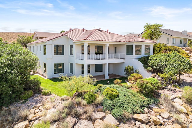 back of property featuring a balcony, a tile roof, and stucco siding