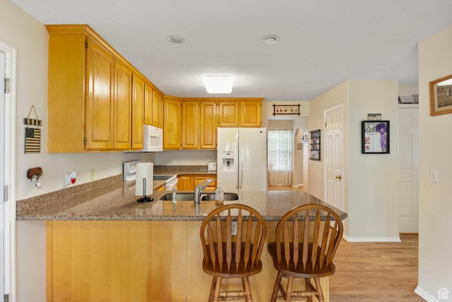 546 E River Meadow Dr S, Alpine, UT 84004 - kitchen with white appliances, light wood-style flooring, a peninsula, dark stone countertops, and a sink