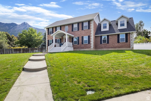 546 E River Meadow Dr S, Alpine, UT 84004 - colonial-style house featuring a front yard, a mountain view, a shingled roof, fence, and brick siding