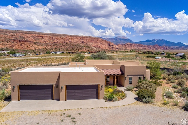 431 E Coronado Ln, Moab, UT 84532 - view of front facade featuring gravel driveway, an attached garage, a mountain view, and stucco siding