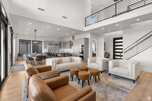 living room featuring a towering ceiling and light hardwood / wood-style floors