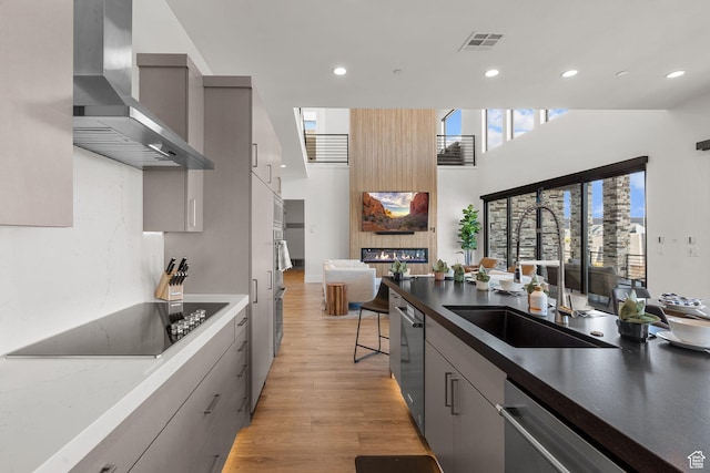 kitchen featuring gray cabinets, black electric stovetop, sink, and wall chimney range hood