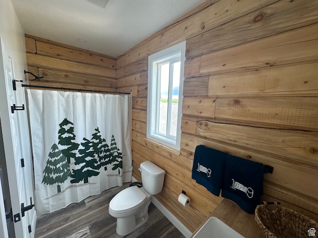 109 Gentle Ben Rd, Fish Haven, ID 83287 - bathroom featuring wooden walls, wood finished floors, a shower with shower curtain, and toilet
