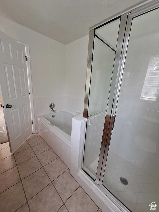 bathroom with tile patterned flooring, a stall shower, and a bath