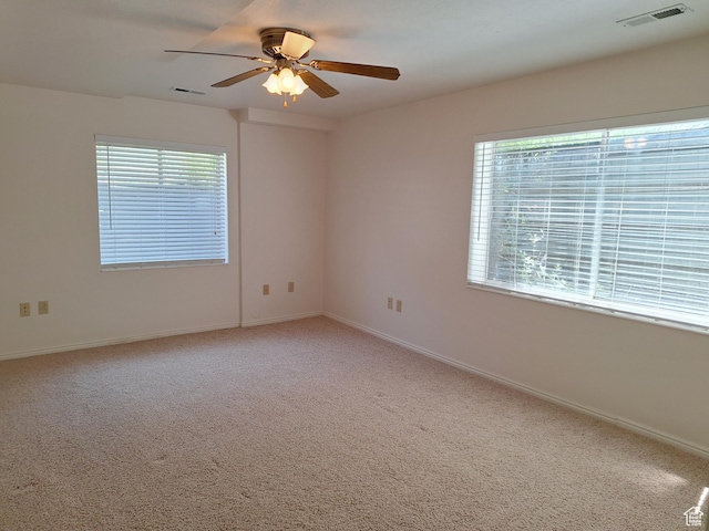unfurnished room featuring visible vents, light carpet, baseboards, and a ceiling fan