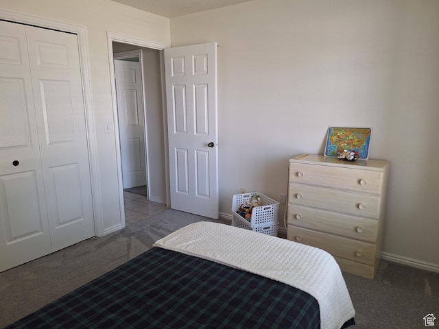 carpeted bedroom with a closet and baseboards