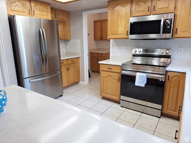 kitchen with light tile patterned floors, stainless steel appliances, decorative backsplash, and light countertops