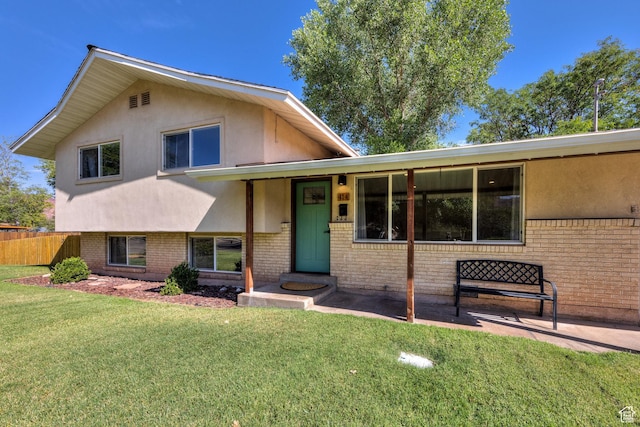 414 W Park Dr W Unit 14, Moab, UT 84532 - split level home with brick siding, stucco siding, fence, and a front lawn