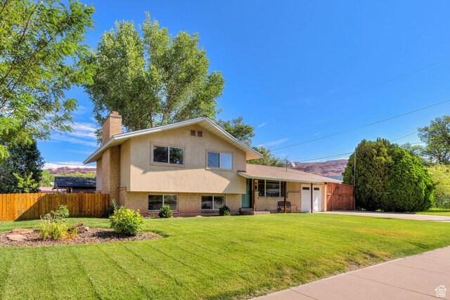 414 W Park Dr W Unit 14, Moab, UT 84532 - tri-level home featuring fence, an attached garage, a chimney, brick siding, and driveway