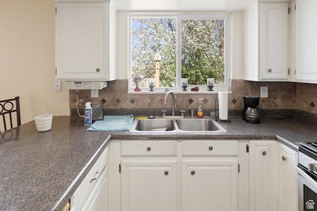 kitchen featuring tasteful backsplash, a sink, white cabinets, and dark countertops
