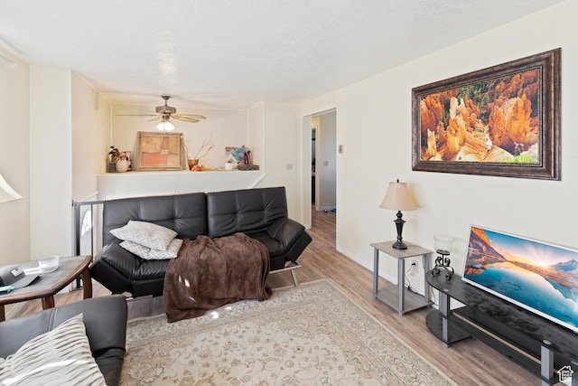 living area featuring wood finished floors, baseboards, and a ceiling fan