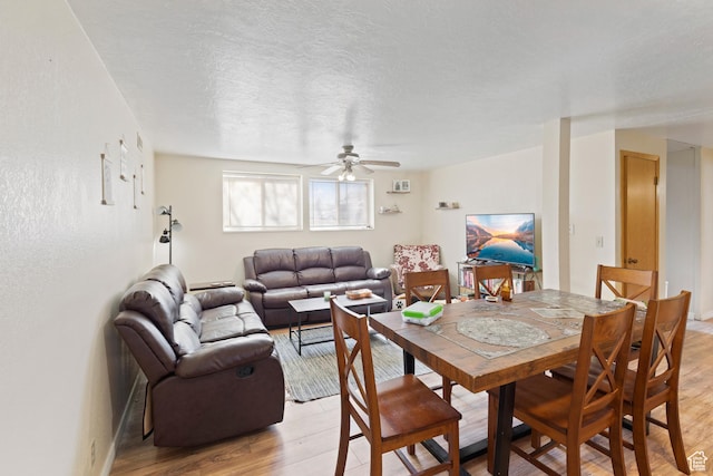 dining room featuring light wood-style flooring, a textured ceiling, and ceiling fan