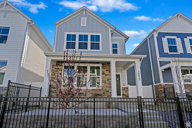 10033 N Torreya Dr Unit 737, Highland, UT 84003 - view of front facade featuring stone siding, a porch, a fenced front yard, and board and batten siding