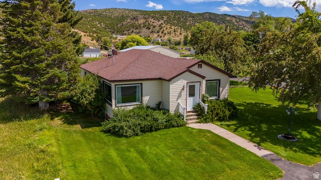 bungalow-style house featuring a shingled roof, a front yard, and a mountain view