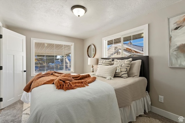 bedroom with carpet, baseboards, and a textured ceiling