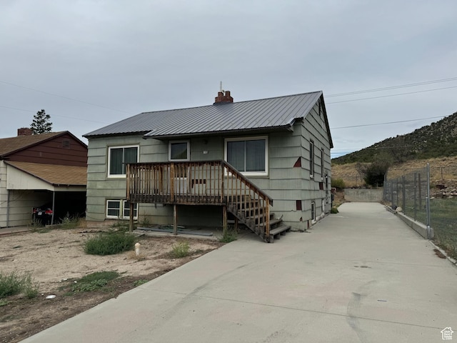 531 Edgehill Dr, Sunnyside, UT 84539 - view of front of house with a chimney, a wooden deck, fence, and metal roof