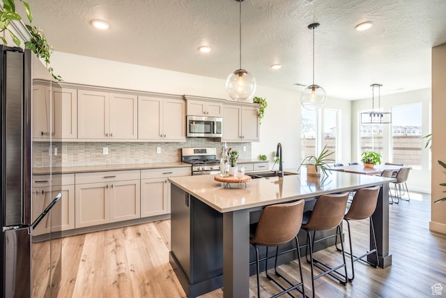 581 W Cypress Umber Dr Unit 34, St George, UT 84790 - kitchen with appliances with stainless steel finishes, a sink, a breakfast bar, light wood-style floors, and tasteful backsplash