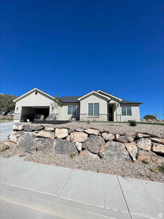 ranch-style house featuring stone siding, an attached garage, and stucco siding