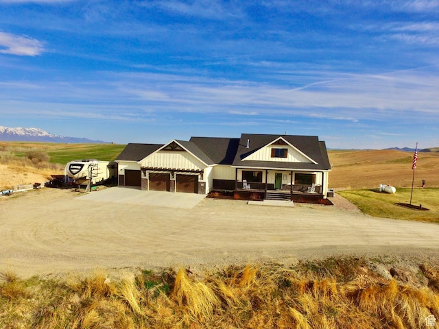 view of front of home featuring a mountain view, covered porch, a garage, board and batten siding, and driveway