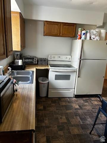 kitchen with a sink, stone finish flooring, white appliances, brown cabinetry, and a toaster