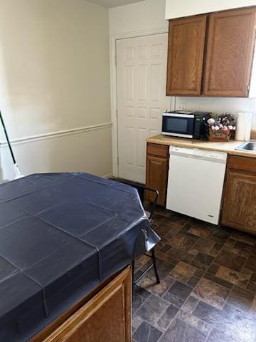kitchen featuring a sink, dishwasher, and brown cabinetry