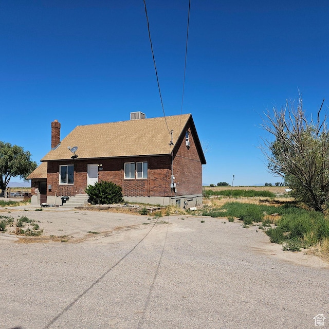 back of house featuring entry steps, brick siding, and a chimney