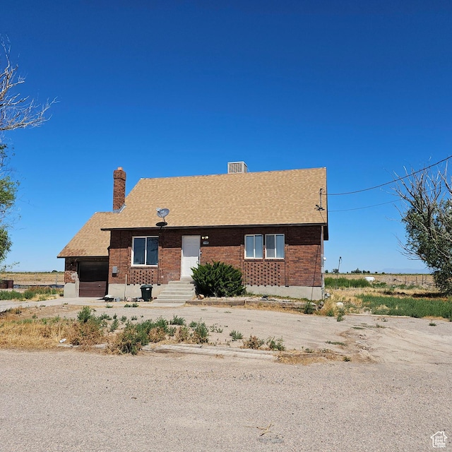 view of front of property featuring a garage, driveway, and a chimney
