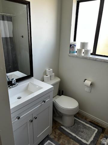 bathroom featuring a shower with curtain, baseboards, toilet, and vanity