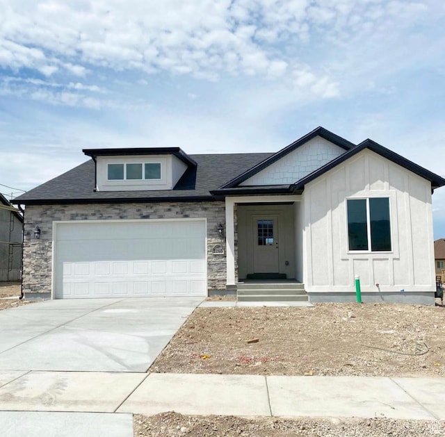 view of front of property with an attached garage, board and batten siding, stone siding, and concrete driveway