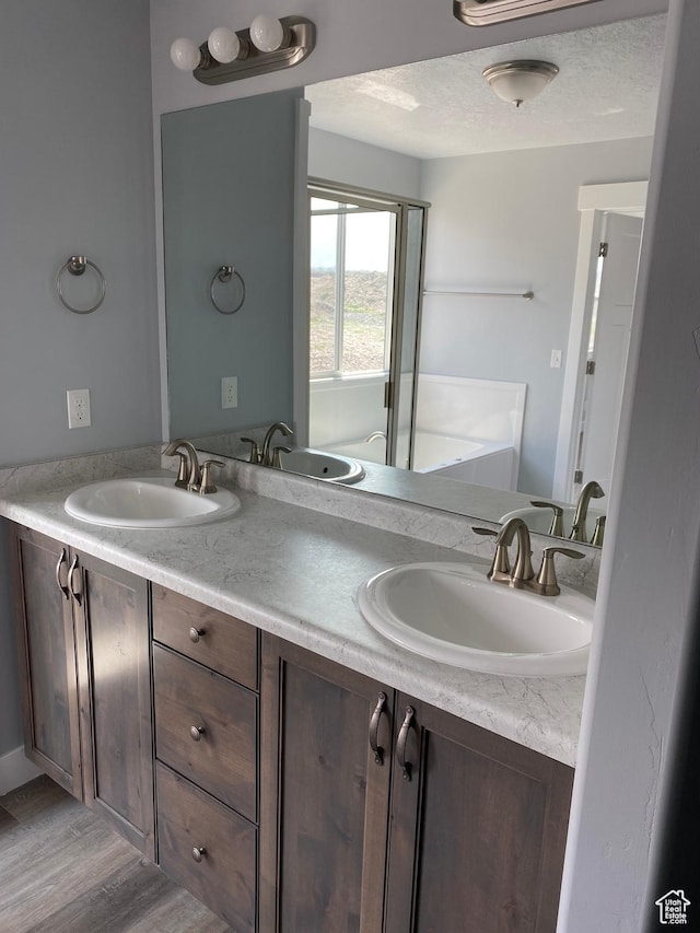 full bathroom featuring double vanity, a sink, and wood finished floors