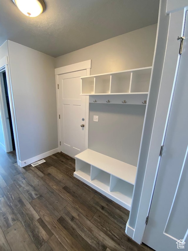 mudroom featuring baseboards, dark wood finished floors, a textured ceiling, and visible vents