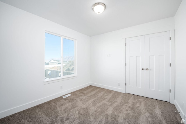 unfurnished bedroom with carpet floors, baseboards, a closet, and visible vents