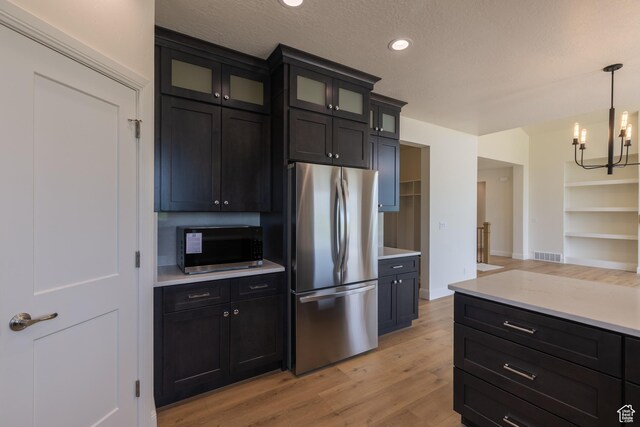 52 W 650 N Unit 3, Salem, UT 84653 - kitchen with appliances with stainless steel finishes, light countertops, light wood finished floors, a chandelier, and glass insert cabinets
