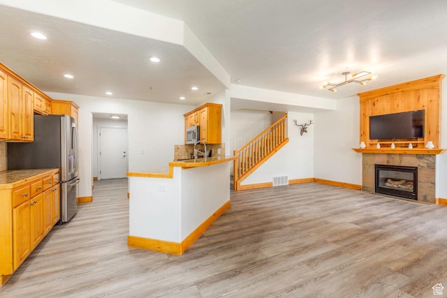 1746 W Redstone Ave # G, Park City, UT 84098 - kitchen with appliances with stainless steel finishes, backsplash, sink, light hardwood / wood-style flooring, and a fireplace