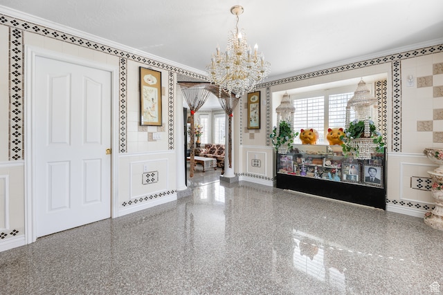 entryway with a decorative wall, an inviting chandelier, ornamental molding, and a wainscoted wall