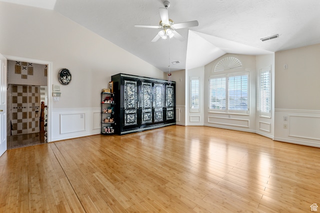 spare room featuring a decorative wall, lofted ceiling, and a wainscoted wall