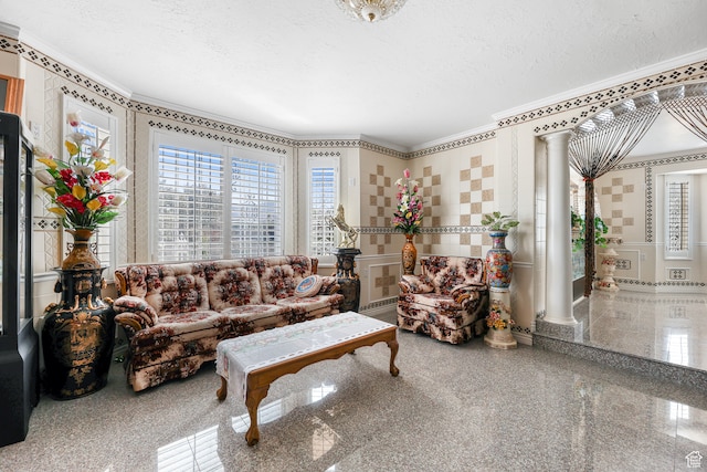 living area with ornamental molding, a textured ceiling, granite finish floor, ornate columns, and a decorative wall