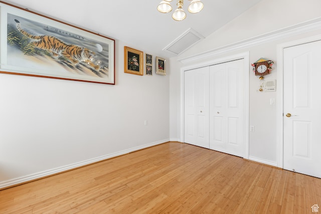 unfurnished bedroom featuring light wood-style flooring, a closet, baseboards, and vaulted ceiling