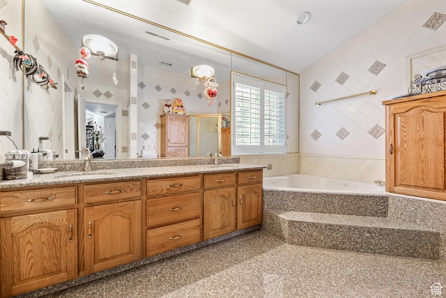 bathroom featuring a sink, a shower stall, double vanity, and a garden tub