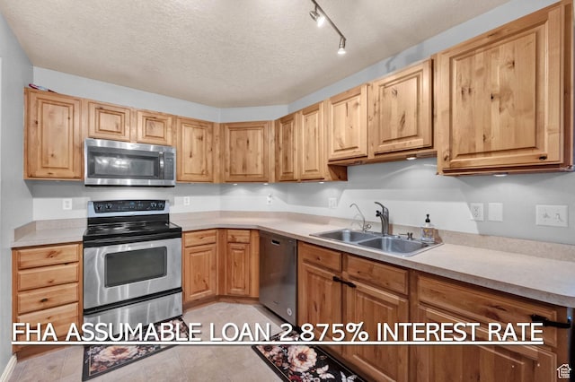 kitchen featuring light tile patterned floors, light countertops, a textured ceiling, stainless steel appliances, and a sink