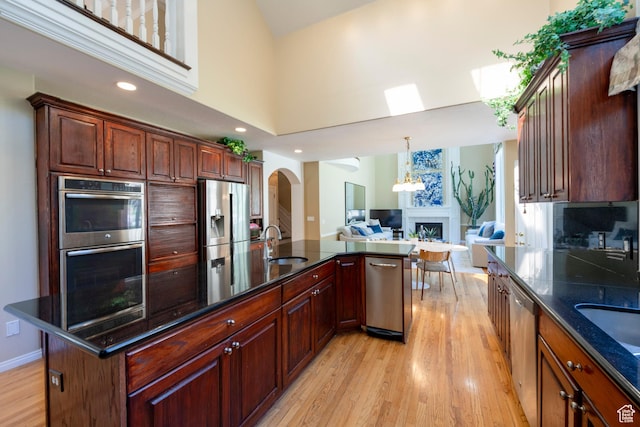 3880 E Thousand Oaks Cir, Salt Lake City, UT 84124 - kitchen with light wood-style flooring, arched walkways, a sink, appliances with stainless steel finishes, and open floor plan