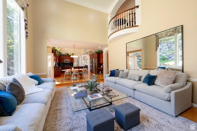 3880 E Thousand Oaks Cir, Salt Lake City, UT 84124 - living area featuring arched walkways, an inviting chandelier, a high ceiling, and light wood-style floors
