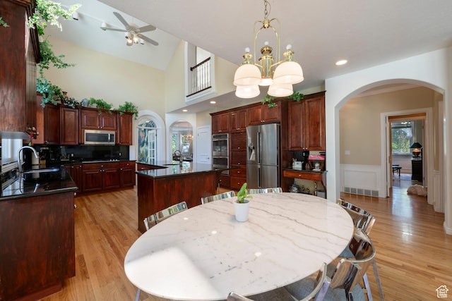 3880 E Thousand Oaks Cir, Salt Lake City, UT 84124 - dining room featuring light wood-type flooring, a wainscoted wall, ceiling fan with notable chandelier, arched walkways, and lofted ceiling